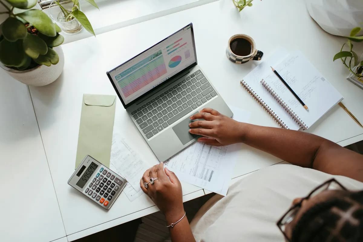 Business owner reviewing a finance dashboard on a laptop with a calculator and invoices on the desk