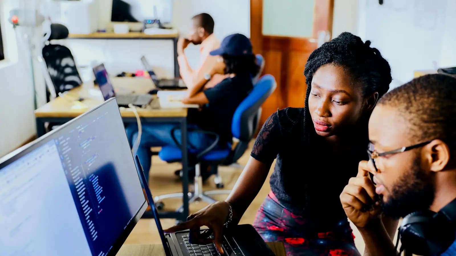 Two software developers reviewing code together on a monitor — custom software development company in Kerala